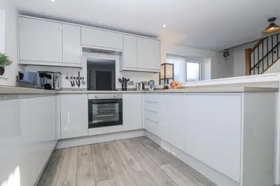 a kitchen with white cabinets and a wooden floor at Cosy Retreat in Camborne