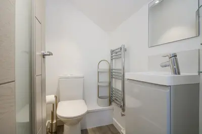 a white bathroom with a toilet and a sink at Cosy Retreat in Camborne