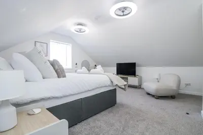 a white bedroom with a large bed and a chair at Cosy Retreat in Camborne