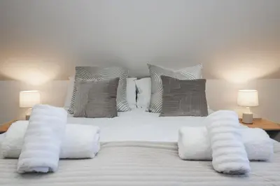 a large white bed with white pillows and two lamps at Cosy Retreat in Camborne