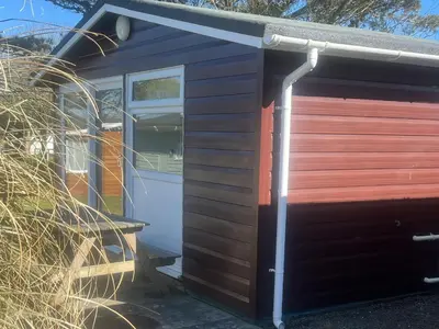 a garage with a wooden door next to a pile of hay at Stanbury in Padstow