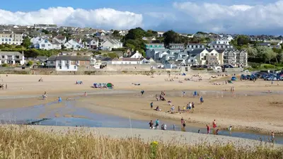 a group of people on a beach with houses at Holiday Home with Hot Tub Cornish Country SeaSide in Porth