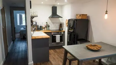 a kitchen with a table and a black refrigerator at Mor Ki -A perfectly situated modern flat in Looe in Looe
