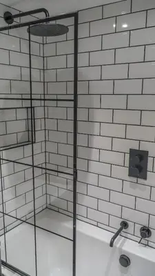 a glass shower in a bathroom with white tiles at Mor Ki -A perfectly situated modern flat in Looe in Looe