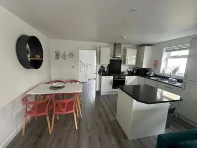 a kitchen with a table and red chairs in a room at Wave Side Lodge 106B- Retallack Resort & Spa in Saint Columb Major