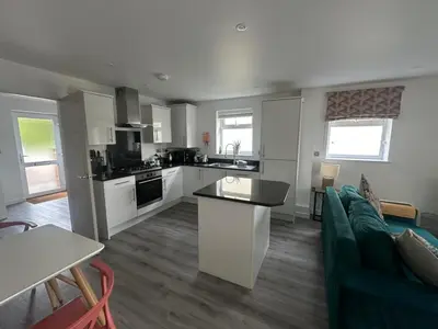 a kitchen and living room with a couch and a table at Wave Side Lodge 106B- Retallack Resort & Spa in Saint Columb Major