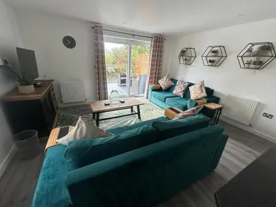 a living room with two blue couches and a table at Wave Side Lodge 106B- Retallack Resort & Spa in Saint Columb Major