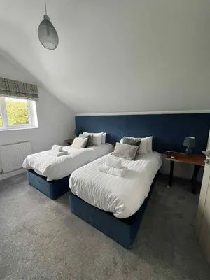 two beds in a bedroom with a blue headboard at Wave Side Lodge 106B- Retallack Resort & Spa in Saint Columb Major