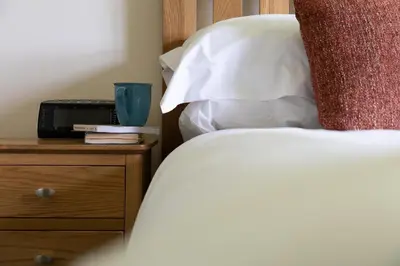 a close up of a bed with a night stand with a bed sidx sidx sidx at Fuchsia Cottage in Saint Endellion