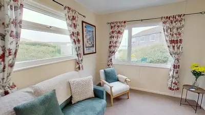 a living room with a couch and a chair and a window at D17 Vellanoweth, Riviere Towans in Hayle