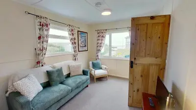a living room with a blue couch and a window at D17 Vellanoweth, Riviere Towans in Hayle