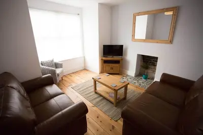 a living room with a couch and a table and a television at Stone's Throw // Central Newquay // Parking in Newquay