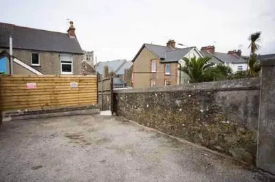 a wooden fence in front of a yard with houses at Stone's Throw // Central Newquay // Parking in Newquay