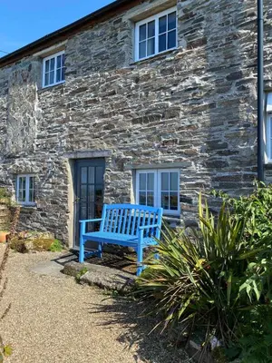 a blue bench sitting in front of a stone building at Buntings Cottage at Trenale Court Cottages in Tintagel