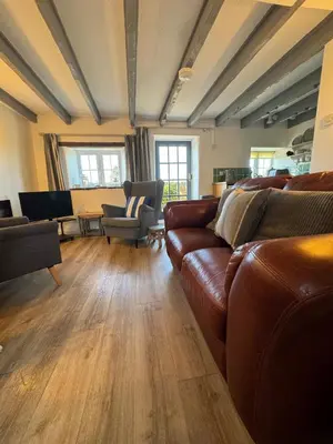a living room with a leather couch and chairs at Buntings Cottage at Trenale Court Cottages in Tintagel