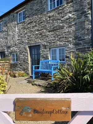 a blue bench sitting in front of a stone building at Buntings Cottage at Trenale Court Cottages in Tintagel