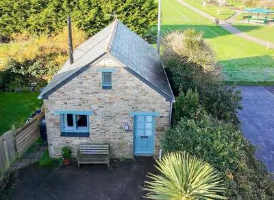 an old stone house with a blue door and a bench at Bramble Cottage in Saint Columb Minor