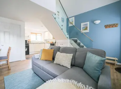 a living room with a couch and a staircase at Bramble Cottage in Saint Columb Minor