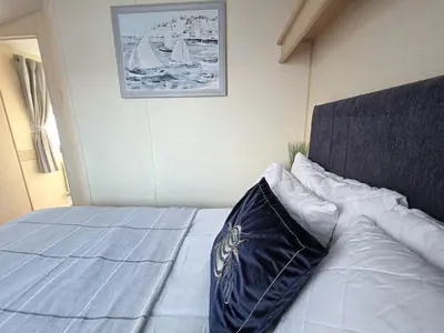 a bed with a blue blanket and pillows on it at Ocean Breeze in Truro