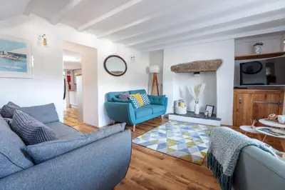 a living room with two blue couches and a tv at Wavecrest in Portreath