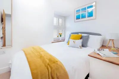 a bedroom with a white bed with a yellow blanket on it at Wavecrest in Portreath