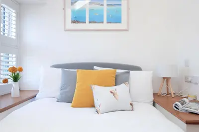 a white bedroom with a bed with yellow and white pillows at Wavecrest in Portreath