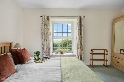 a bedroom with a bed and a window at Rose Cottage in Port Isaac