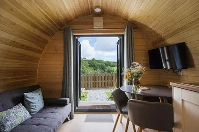 a living room with a couch and a table and a window at Polgooth Inn in St Austell