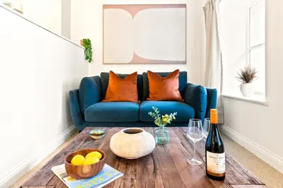 a blue couch in a living room with a wooden table at Ye Old Mill - Stylish cosy retreat with parking in Penryn