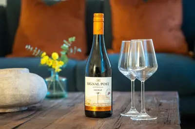 a bottle of wine sitting next to two wine glasses at Ye Old Mill - Stylish cosy retreat with parking in Penryn