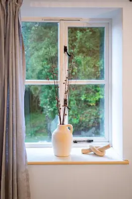 a white vase sitting on a window sill with a plant at Ye Old Mill - Stylish cosy retreat with parking in Penryn