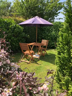 a table and two chairs under an umbrella at Wren Cottage at Trenale Court Cottages in Tintagel