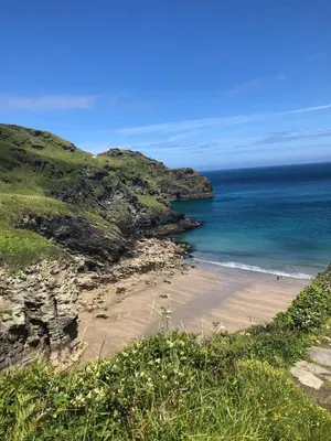 a view of a beach with people in the water at Wren Cottage at Trenale Court Cottages in Tintagel