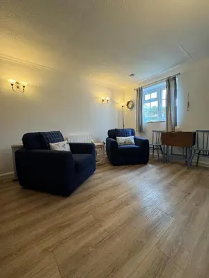 a living room with two couches and a table at Wren Cottage at Trenale Court Cottages in Tintagel