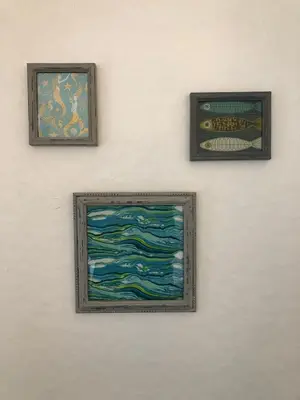 three framed pictures of the ocean on a wall at Wren Cottage at Trenale Court Cottages in Tintagel