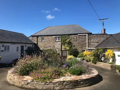 a stone house with a garden in front of it at Wren Cottage at Trenale Court Cottages in Tintagel