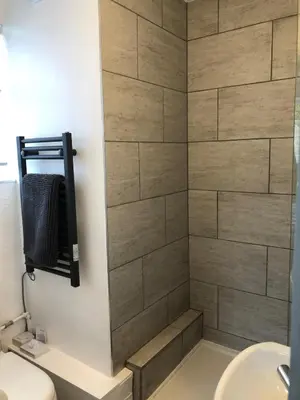 a shower in a bathroom with a stone wall at Wren Cottage at Trenale Court Cottages in Tintagel