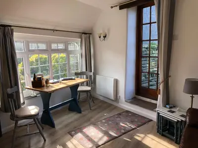 a room with a desk with chairs and a window at Plover Cottage at Trenale Court Cottages in Tintagel