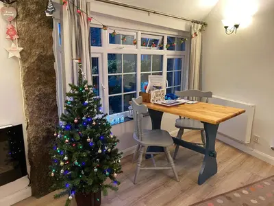 a room with a christmas tree and a wooden table at Plover Cottage at Trenale Court Cottages in Tintagel