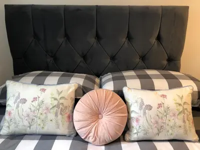 two pillows on a bed with a black headboard at Plover Cottage at Trenale Court Cottages in Tintagel