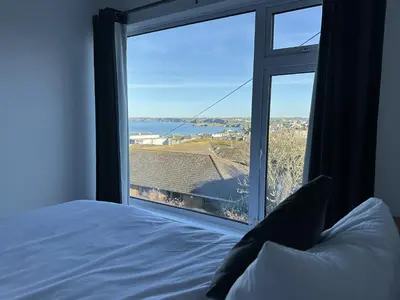 a bedroom with a bed and a large window at Sea Boots in Newquay