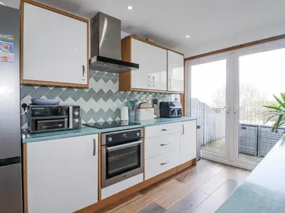 a kitchen with white cabinets and a stove top oven at Sea Boots in Newquay