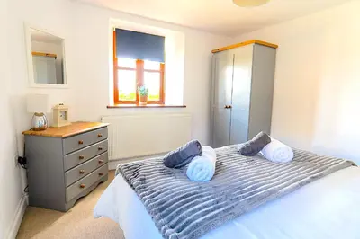 a bedroom with a bed with blue pillows and a dresser at Finest Retreats - Fields Barn in Widemouth Bay