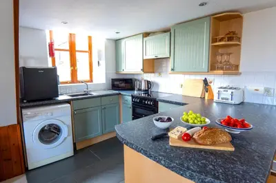 a kitchen with green cabinets and vegetables on a counter at Finest Retreats - Fields Barn in Widemouth Bay