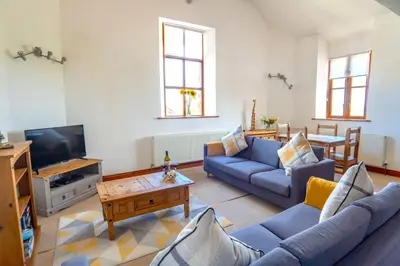 a living room with blue couches and a tv at Finest Retreats - Fields Barn in Widemouth Bay