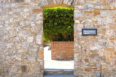 an entrance to a stone building with a sign on it at Finest Retreats - Rosemary Cottage in Widemouth Bay