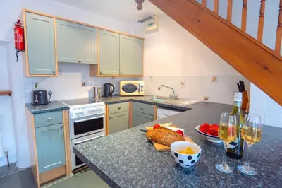a kitchen with a counter with two glasses of wine at Finest Retreats - Rosemary Cottage in Widemouth Bay