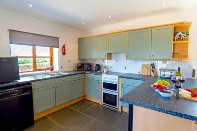 a kitchen with green cabinets and a counter top at Finest Retreats - Olive Tree in Widemouth Bay
