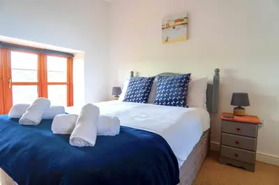 a bedroom with a large bed with blue and white pillows at Finest Retreats - Olive Tree in Widemouth Bay