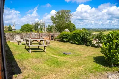 a picnic table in the yard of a stone house at Finest Retreats - Olive Tree in Widemouth Bay